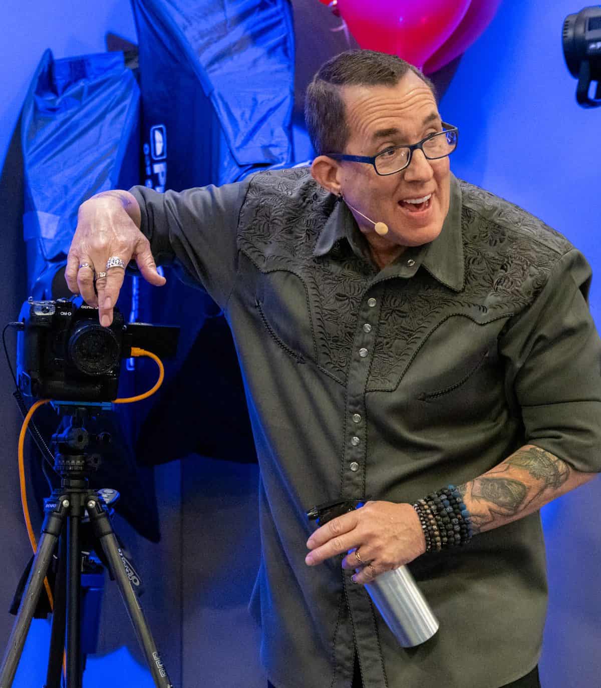 A man holding a camera in front of a room full of balloons.